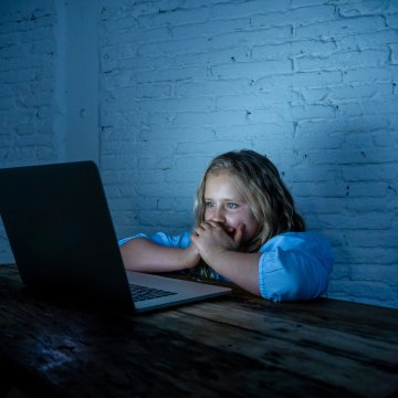 Child in front of laptop looking upset 